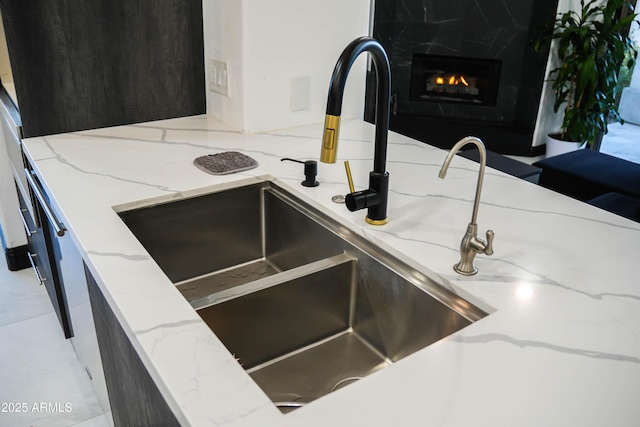 interior details featuring light stone counters, a sink, and a high end fireplace