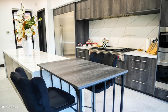 kitchen with a breakfast bar area, light countertops, decorative backsplash, appliances with stainless steel finishes, and modern cabinets