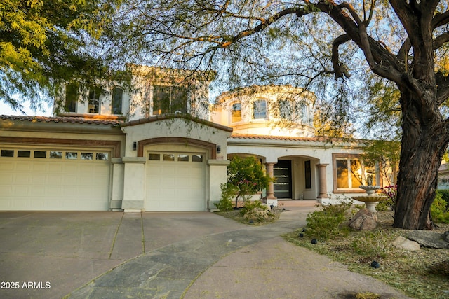 mediterranean / spanish house with a tile roof, driveway, an attached garage, and stucco siding