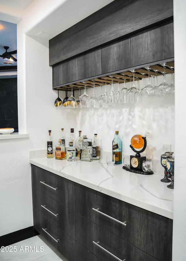 bar featuring a ceiling fan, baseboards, and a dry bar