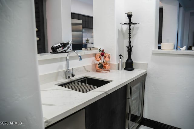 kitchen with beverage cooler, a sink, and dark cabinets