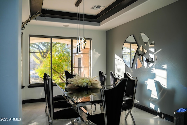 dining area with finished concrete floors, a raised ceiling, visible vents, and baseboards