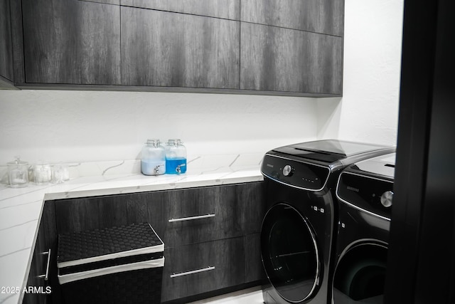 clothes washing area featuring cabinet space and washer and dryer