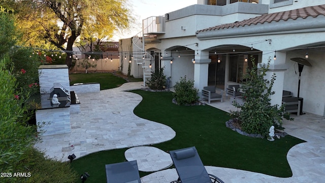 view of yard with fence, exterior kitchen, and a patio