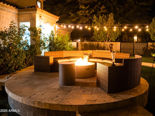 patio at night with a fire pit and fence