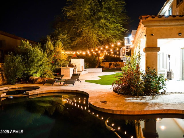 patio at twilight with an in ground hot tub, stairway, a fireplace, and an outdoor pool