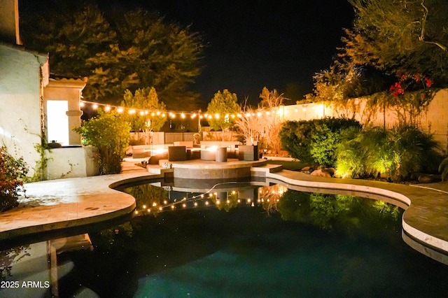 pool at night with a patio, a fenced backyard, and a fenced in pool