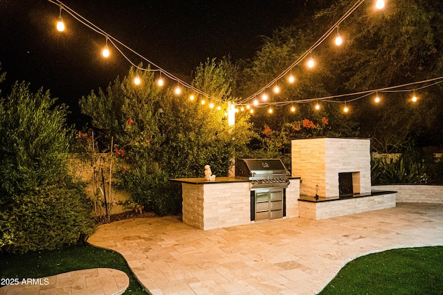 patio at night featuring area for grilling