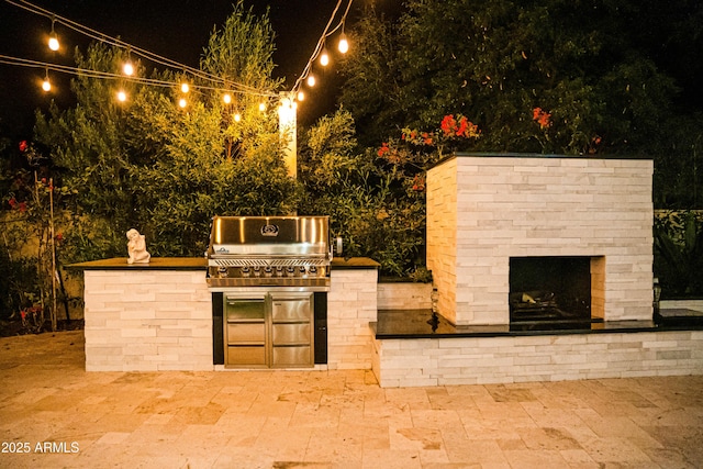 patio at night featuring a grill and area for grilling