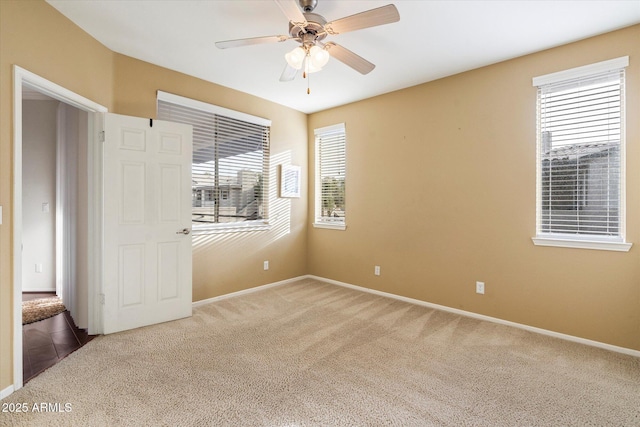 unfurnished room with ceiling fan, carpet floors, and a wealth of natural light