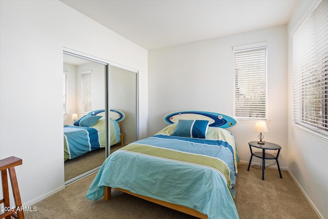 bedroom with a closet, light colored carpet, and baseboards