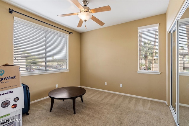 sitting room featuring baseboards, a ceiling fan, and light colored carpet