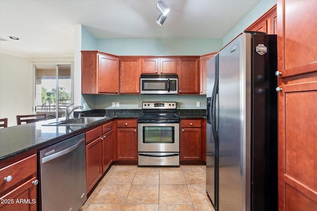 kitchen with sink, dark stone counters, appliances with stainless steel finishes, and light tile patterned flooring