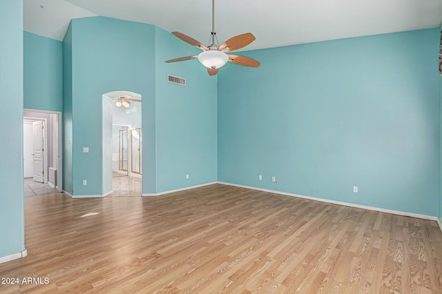 empty room with high vaulted ceiling, light hardwood / wood-style flooring, and ceiling fan