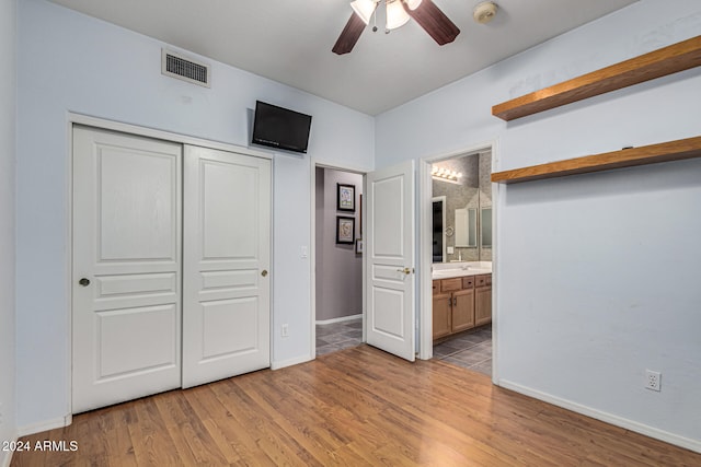 unfurnished bedroom featuring a closet, ensuite bathroom, light hardwood / wood-style flooring, and ceiling fan