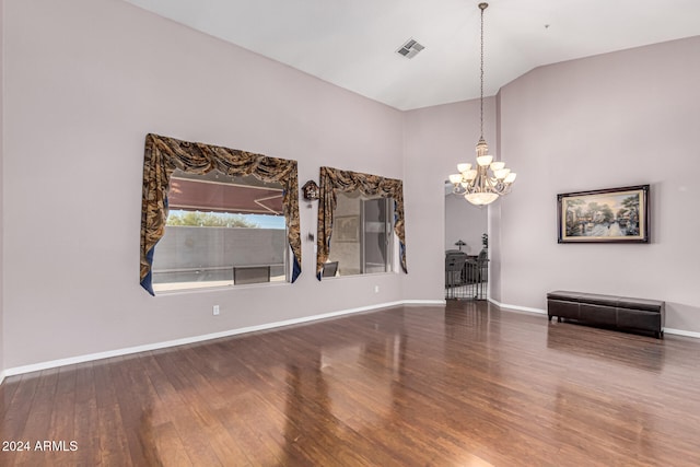 spare room featuring hardwood / wood-style flooring, lofted ceiling, and a chandelier