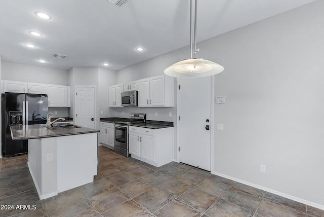 kitchen with appliances with stainless steel finishes, white cabinetry, a kitchen island with sink, and sink