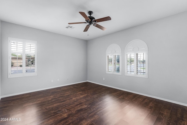 spare room with dark hardwood / wood-style flooring, a wealth of natural light, and ceiling fan