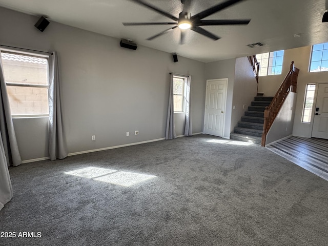 unfurnished living room featuring visible vents, a ceiling fan, carpet, and stairs