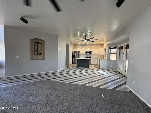 unfurnished living room featuring baseboards, french doors, ceiling fan, light colored carpet, and a sink