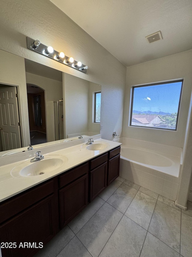 bathroom featuring a sink, visible vents, a bath, and double vanity
