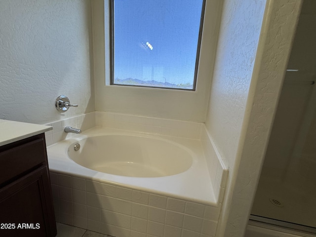 full bathroom with a bath, a textured wall, vanity, and a stall shower