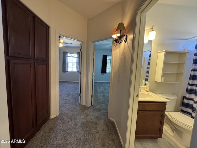 hall featuring a sink, baseboards, and light carpet