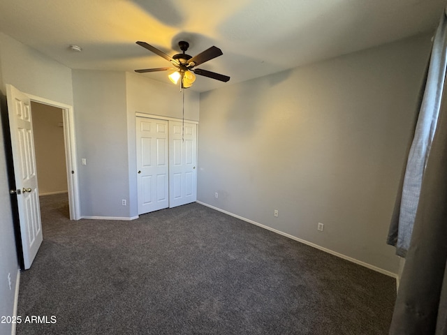 unfurnished bedroom featuring dark carpet, a closet, ceiling fan, and baseboards