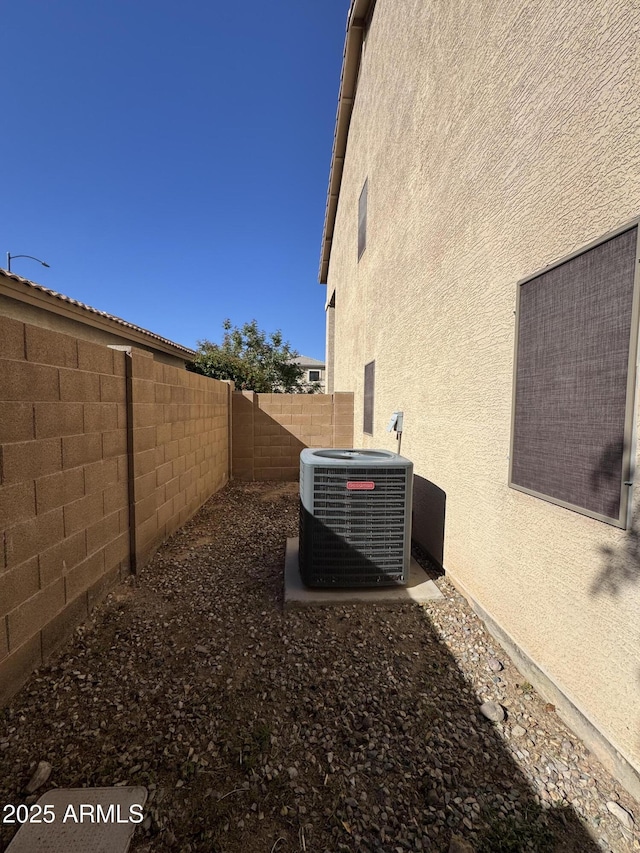 exterior space featuring central AC unit, stucco siding, and a fenced backyard