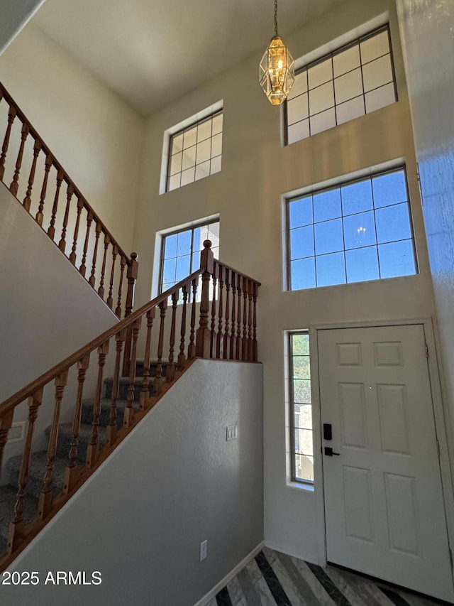 entryway with a chandelier, a towering ceiling, and stairway