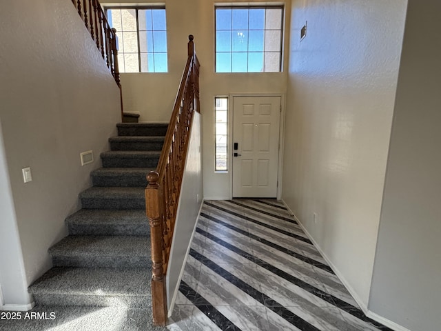 staircase with a towering ceiling and baseboards