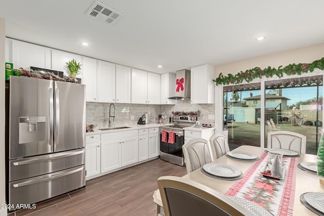 kitchen featuring wall chimney exhaust hood, stainless steel appliances, dark wood-type flooring, sink, and white cabinets