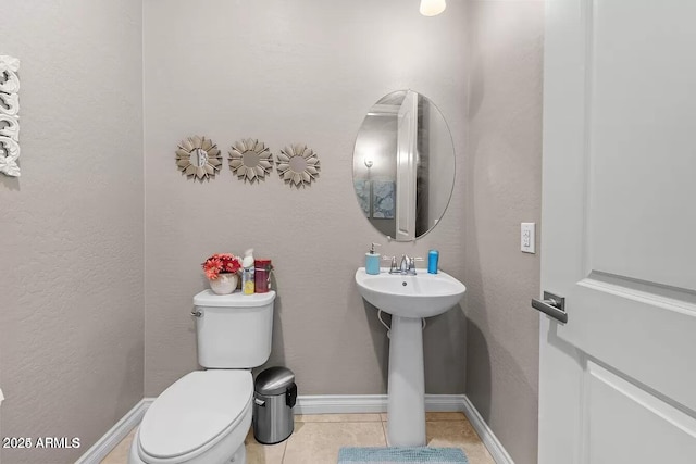 bathroom with toilet, sink, and tile patterned floors