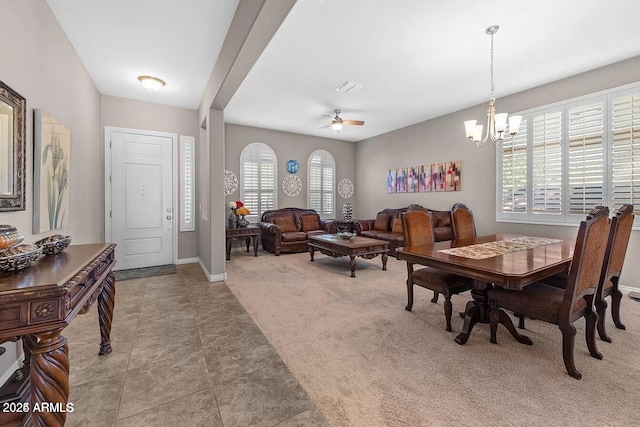 carpeted dining space with ceiling fan with notable chandelier