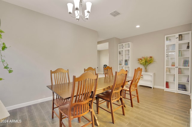 dining area with hardwood / wood-style floors and an inviting chandelier