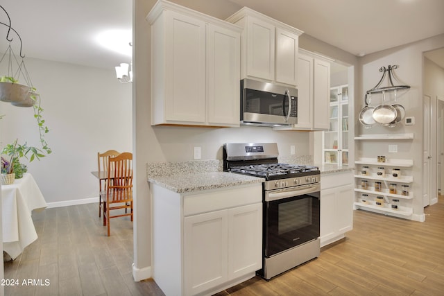 kitchen with white cabinets, light hardwood / wood-style floors, and appliances with stainless steel finishes