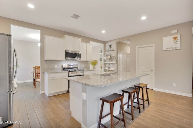 kitchen featuring a center island with sink, white cabinets, stainless steel appliances, and sink