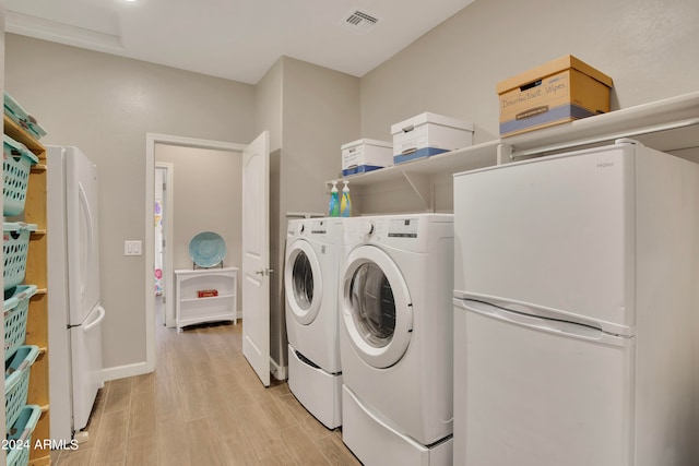 laundry area with washing machine and dryer and light hardwood / wood-style floors