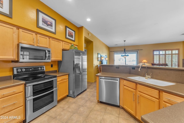 kitchen featuring decorative light fixtures, sink, light brown cabinetry, and stainless steel appliances