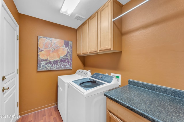 laundry room featuring light wood-type flooring, cabinets, and separate washer and dryer