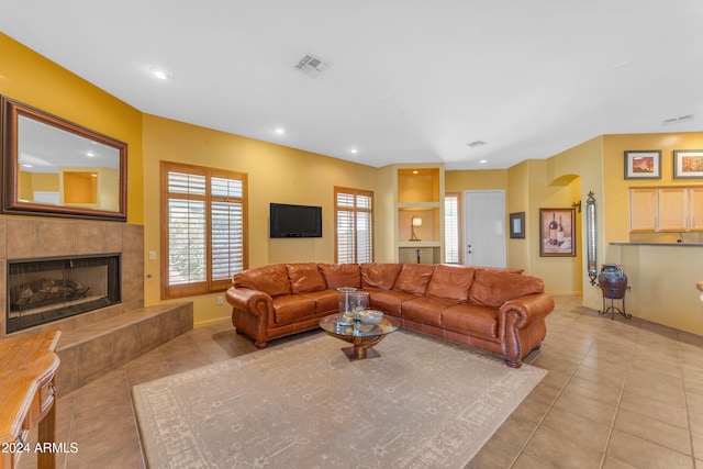 tiled living room featuring built in features and a tiled fireplace