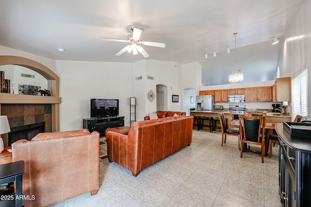 living area featuring visible vents, a tiled fireplace, arched walkways, light tile patterned floors, and ceiling fan