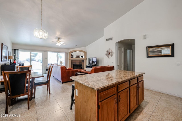 kitchen with light tile patterned floors, visible vents, a kitchen island, and a tiled fireplace