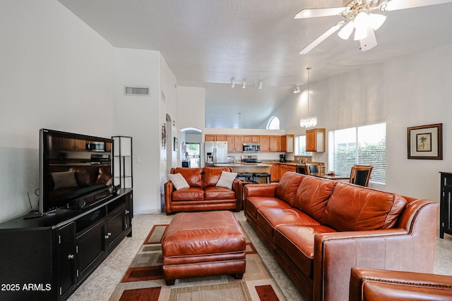 living area featuring visible vents, ceiling fan, rail lighting, arched walkways, and high vaulted ceiling