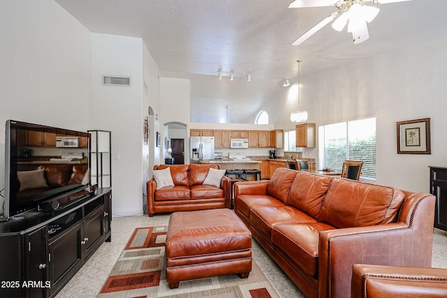 living room with visible vents, track lighting, ceiling fan, arched walkways, and high vaulted ceiling