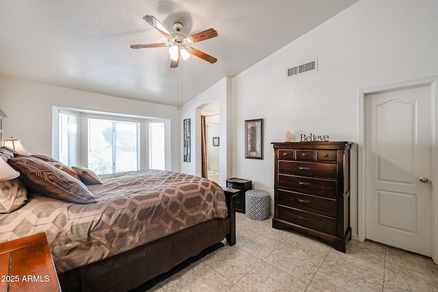 bedroom featuring a ceiling fan, visible vents, arched walkways, vaulted ceiling, and connected bathroom