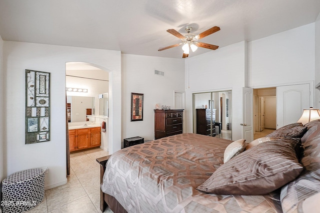 bedroom featuring light tile patterned floors, visible vents, high vaulted ceiling, arched walkways, and a closet