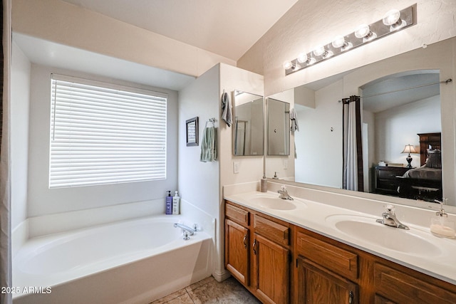 bathroom with a garden tub, double vanity, tile patterned floors, and a sink