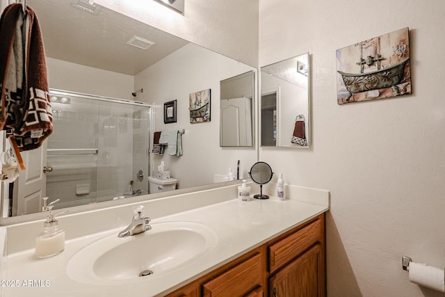 bathroom with visible vents, toilet, vanity, and a textured wall