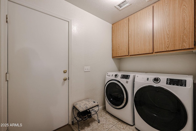 laundry room with visible vents, cabinet space, separate washer and dryer, light tile patterned floors, and baseboards